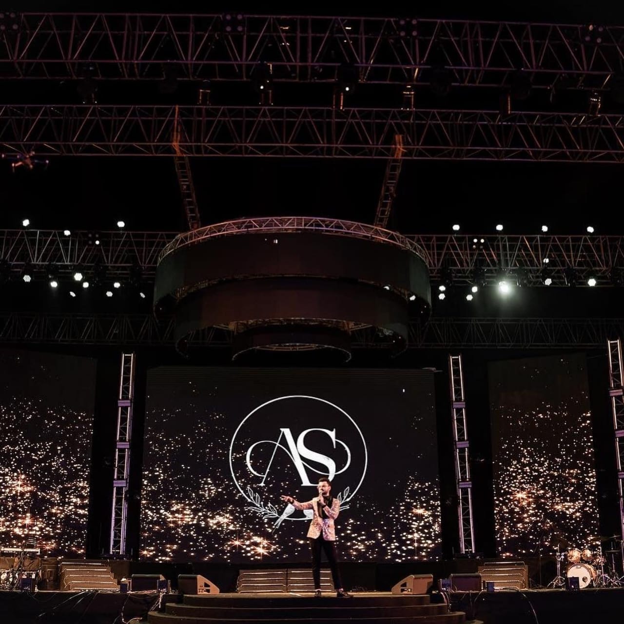 Singer performing on an open-air stage at night
