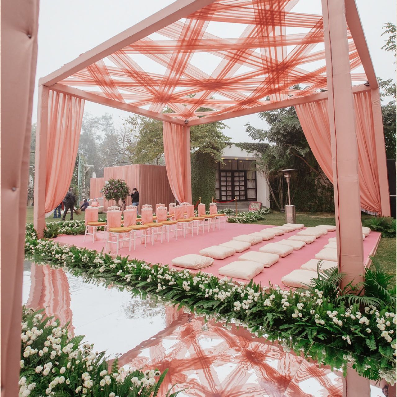 Peach draped pergola ceremony beside a reflecting pool